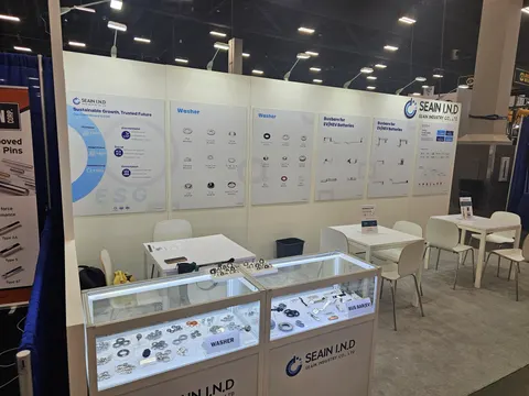 Seain Industry Co., Ltd trade show booth built by Purple Exhibits: Front view of the Seain Industry white inline booth with illuminated glass display cases of metal washers and fasteners, blue sustainability graphics and