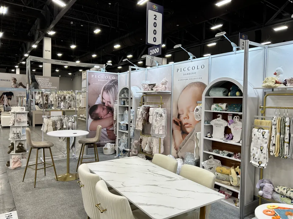 Piccolo Bambino booth by Purple Exhibits: piccolo Bambino baby-products booth with soft pastel infant photography, like the booths we plan for TPIE