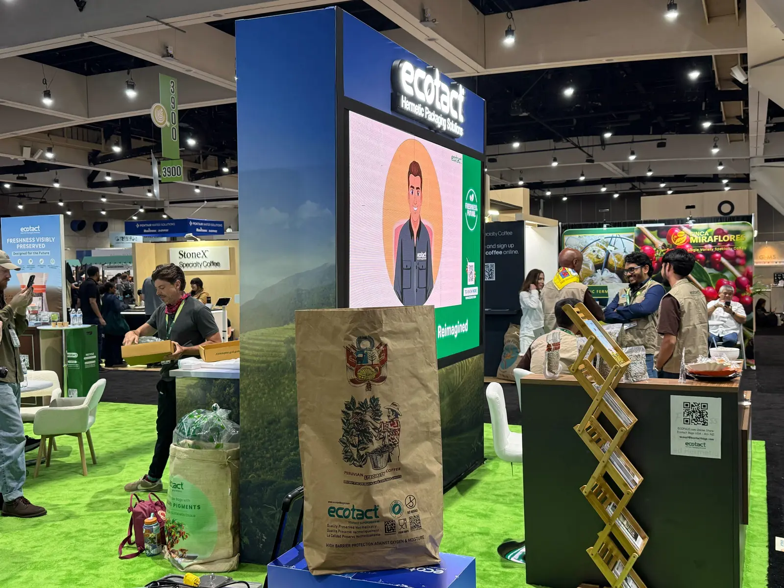 ecotact booth by Purple Exhibits: ecotact coffee-packaging booth with a tall green field-scene graphic tower topped by an