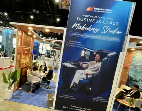 Philippine Airlines trade show booth built by Purple Exhibits: Philippine Airlines booth with a tall dark-blue graphic tower promoting the Mabuhay Studio business class seat, wood-framed structure, lounge seating with vi