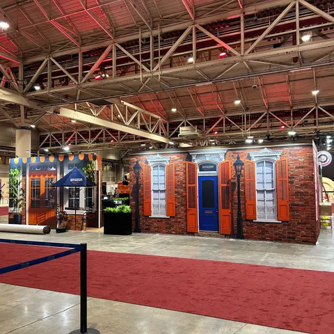 Amazon booth by Purple Exhibits: amazon Quarter environment: a printed brick facade with orange shutters, a blue door