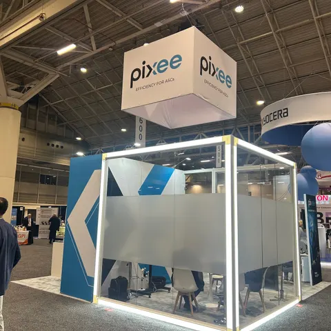 Pixee booth by Purple Exhibits: pixee 'Efficiency for ASCs' island booth with a white hanging cube sign