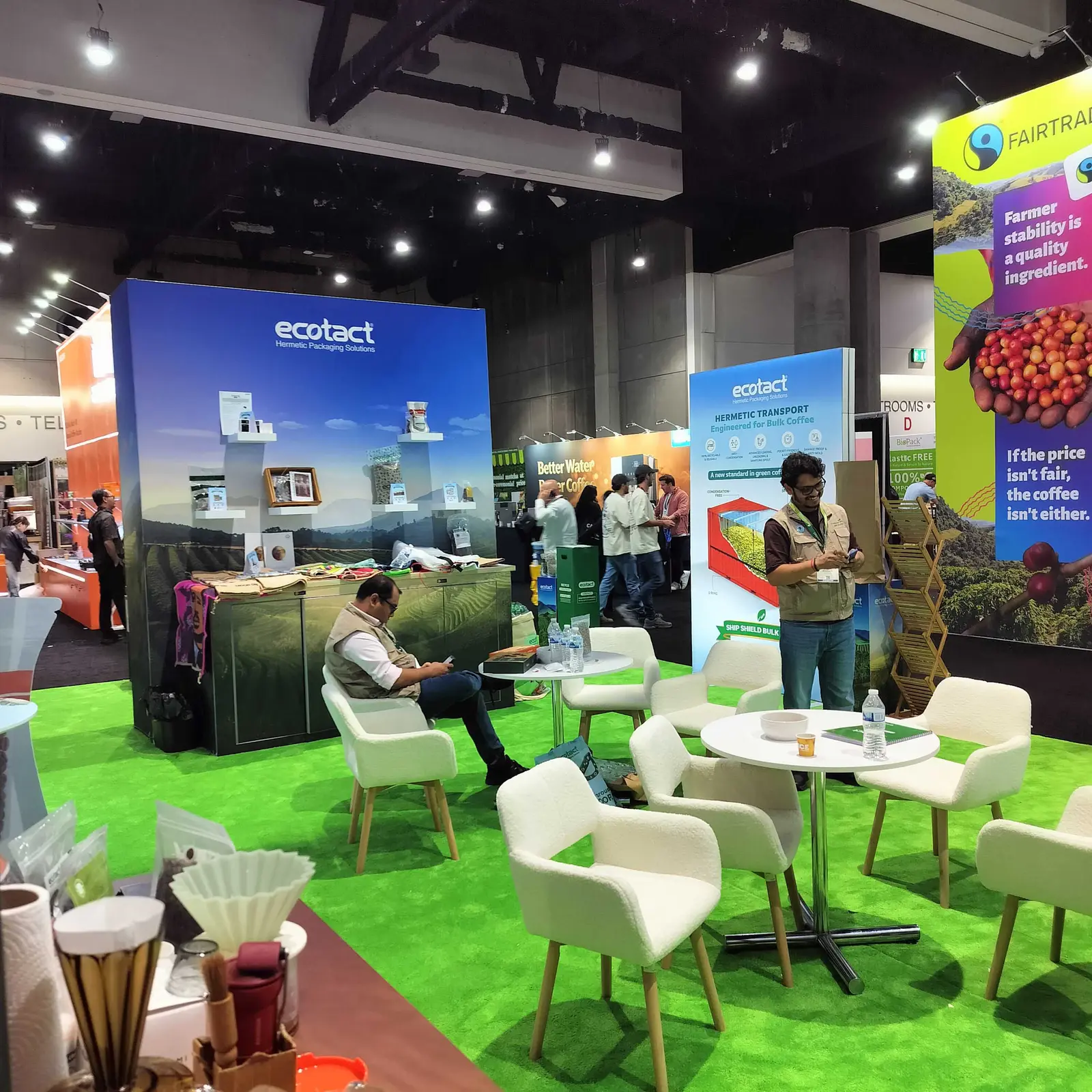 Ecotact booth by Purple Exhibits: open lounge-style Ecotact booth with bright green turf flooring, white armchairs