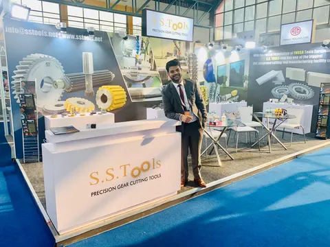 S.S.Tools trade show booth built by Purple Exhibits: White inline booth for S.S.Tools precision gear cutting tools with large gear graphics on the back wall, yellow cutting tools displayed on white plinths, a branded cou