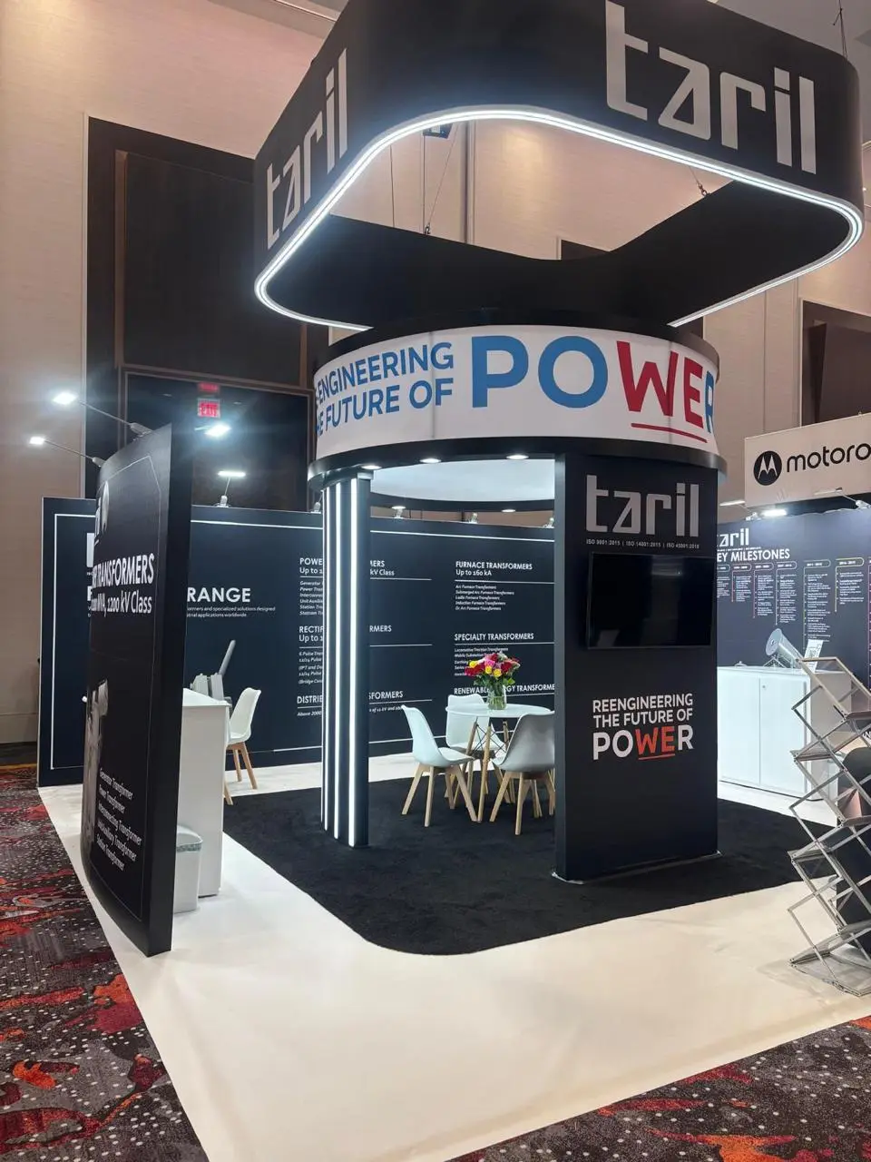 Taril booth by Purple Exhibits: dramatic black Taril transformer booth with a curved illuminated hanging ring, one of our builds to compare for DTECH
