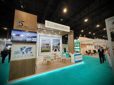 Eagle Chemicals trade show booth built by Purple Exhibits: Alternate angle of the Eagle Chemicals wood-clad island booth showing the '75 Years' anniversary graphic, world-map panel, screen, bistro seating and teal carpet