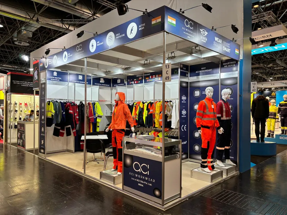 ACI Workwear booth by Purple Exhibits: open white booth with navy graphic headers and a truss-like overhead frame, like the booths we plan for Cosmoprof North America Miami