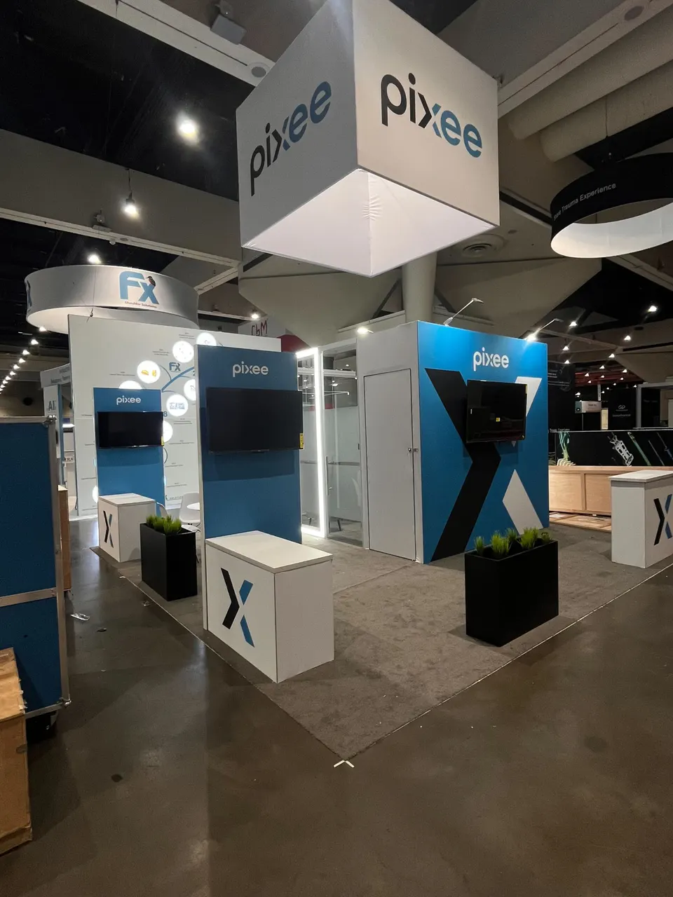Pixee booth by Purple Exhibits: pixee island booth in blue, white and black with a large white cube hanging sign