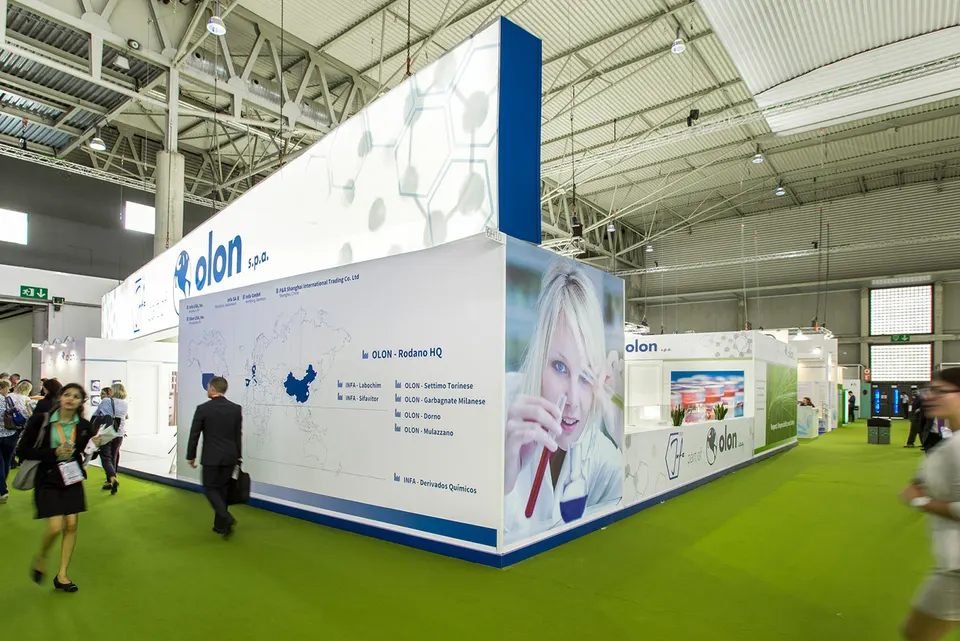Olon S.p.A. booth by Purple Exhibits: tall white Olon pharma booth with blue accents, a world-map site graphic, Purple work to compare for your SCOPE Summit booth