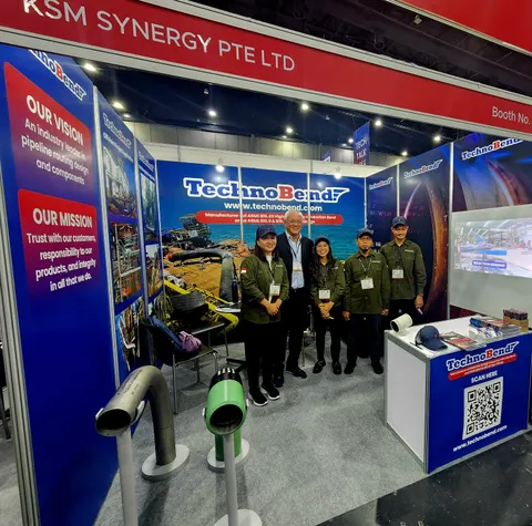 TechnoBend / KSM Synergy Pte Ltd trade show booth built by Purple Exhibits: Five staff posing in the blue and red TechnoBend inline booth under a KSM Synergy header, with pipe bend samples, vision and mission graphics, a
