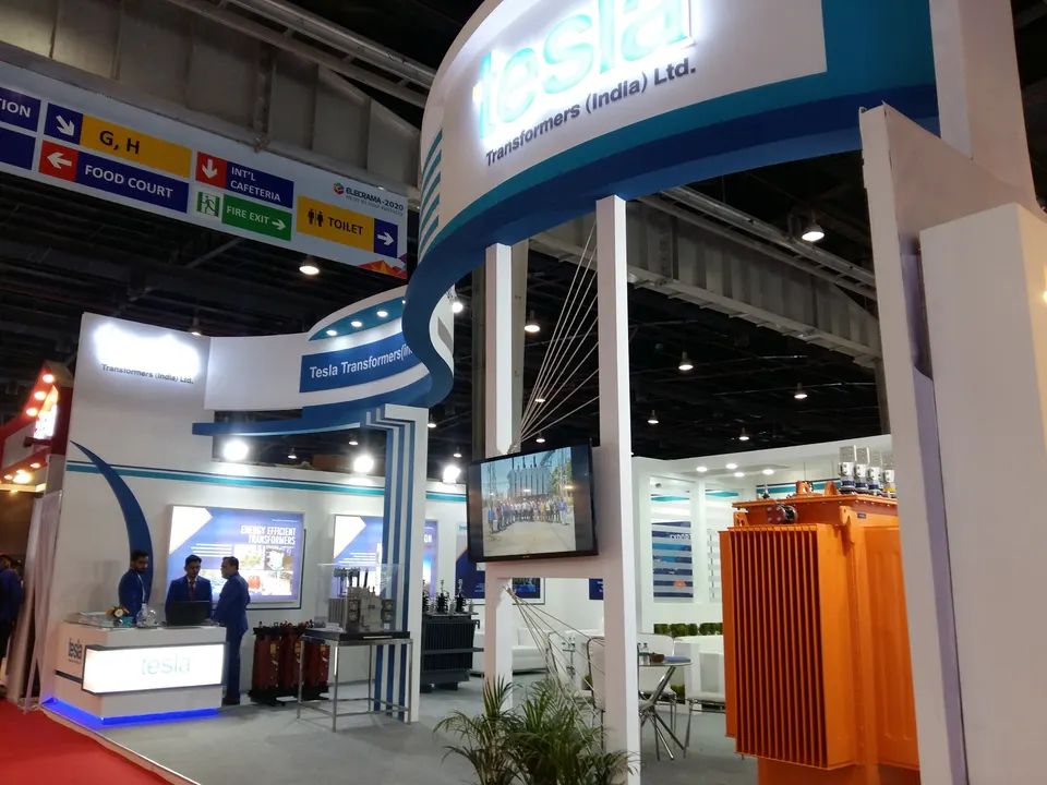 Tesla Transformers (India) Ltd. booth by Purple Exhibits: large white and blue island booth for Tesla Transformers India, an example for ACP OMS exhibitors in Long Beach