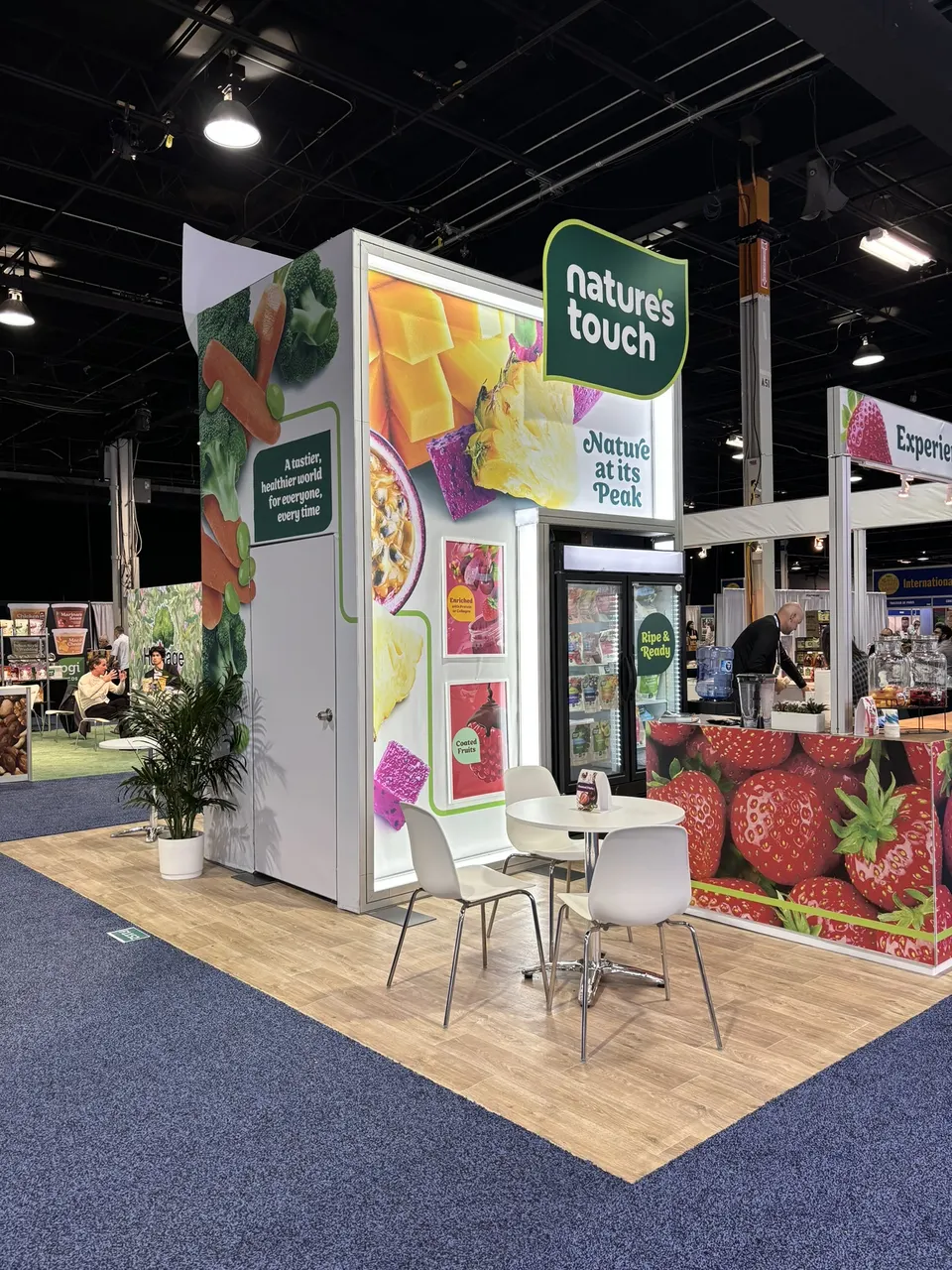 Nature's Touch booth by Purple Exhibits: nature's Touch frozen fruit booth with a tall backlit tower of mango