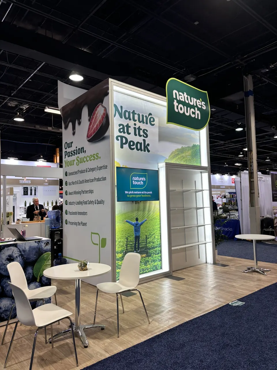 Nature's Touch booth by Purple Exhibits: rear side of the Nature's Touch tower with 'Nature at its Peak' backlit graphic