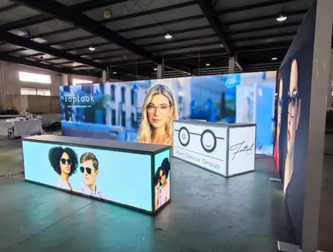Toplook / Kert Optical Group trade show booth built by Purple Exhibits: Backlit eyewear fashion display for Toplook and Kert Optical Group with a long illuminated counter showing models in sunglasses, photographed in a w