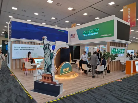 Waaree trade show booth built by Purple Exhibits: Large white and green Waaree booth with a long LED video wall, a Statue of Liberty replica on a wood plinth in front of a circular backlit arch, wood-clad walls, lounge s