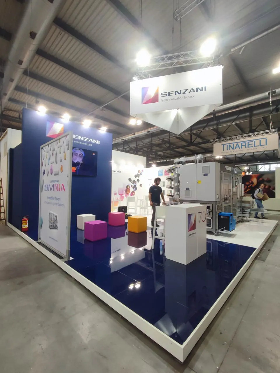 Senzani booth by Purple Exhibits: senzani island booth with a glossy navy-blue raised floor with white edging, the kind of booth we build for FABTECH