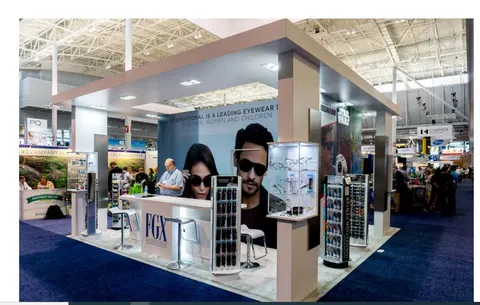 FGX booth by Purple Exhibits: taupe and white island eyewear booth with a large canopy header