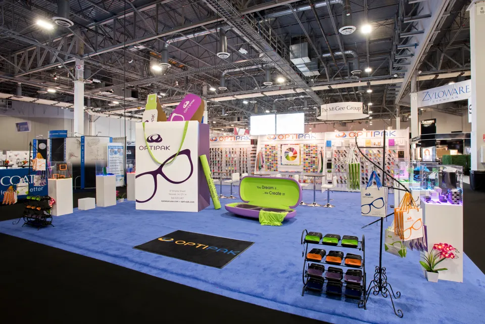 Optipak booth by Purple Exhibits: clean wide shot of the Optipak island booth with blue carpet, white pedestals, like the booths we plan for Vision Expo