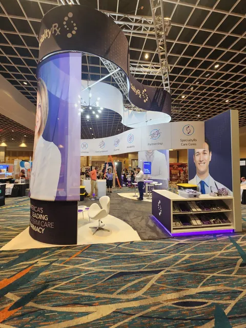 SpecialtyRx booth by Purple Exhibits: island booth for SpecialtyRx with a tall curved purple-and-white graphic tower