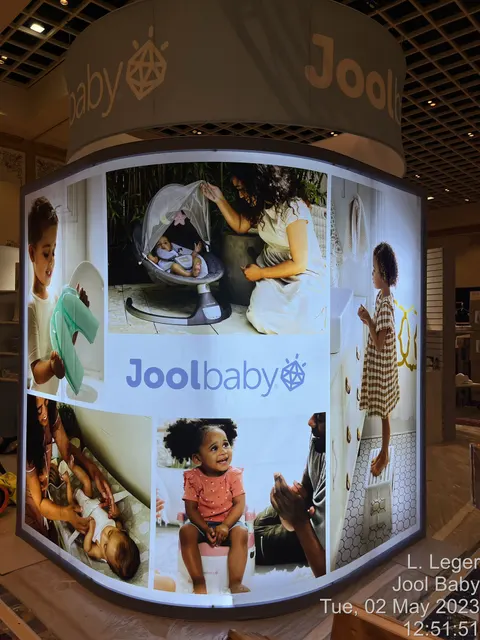 Jool Baby booth by Purple Exhibits: curved backlit lightbox wall with a collage of family and baby lifestyle photos
