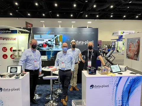 data-pixel trade show booth built by Purple Exhibits: Inline booth with dark navy fabric back wall printed with fiber inspection imagery, a white data-pixel branded counter with demo tablets, bar-height tables and four m