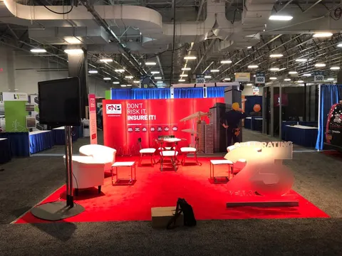 GNP booth by Purple Exhibits: inline booth with red carpet, a red back wall reading Don't Risk It, Insure It