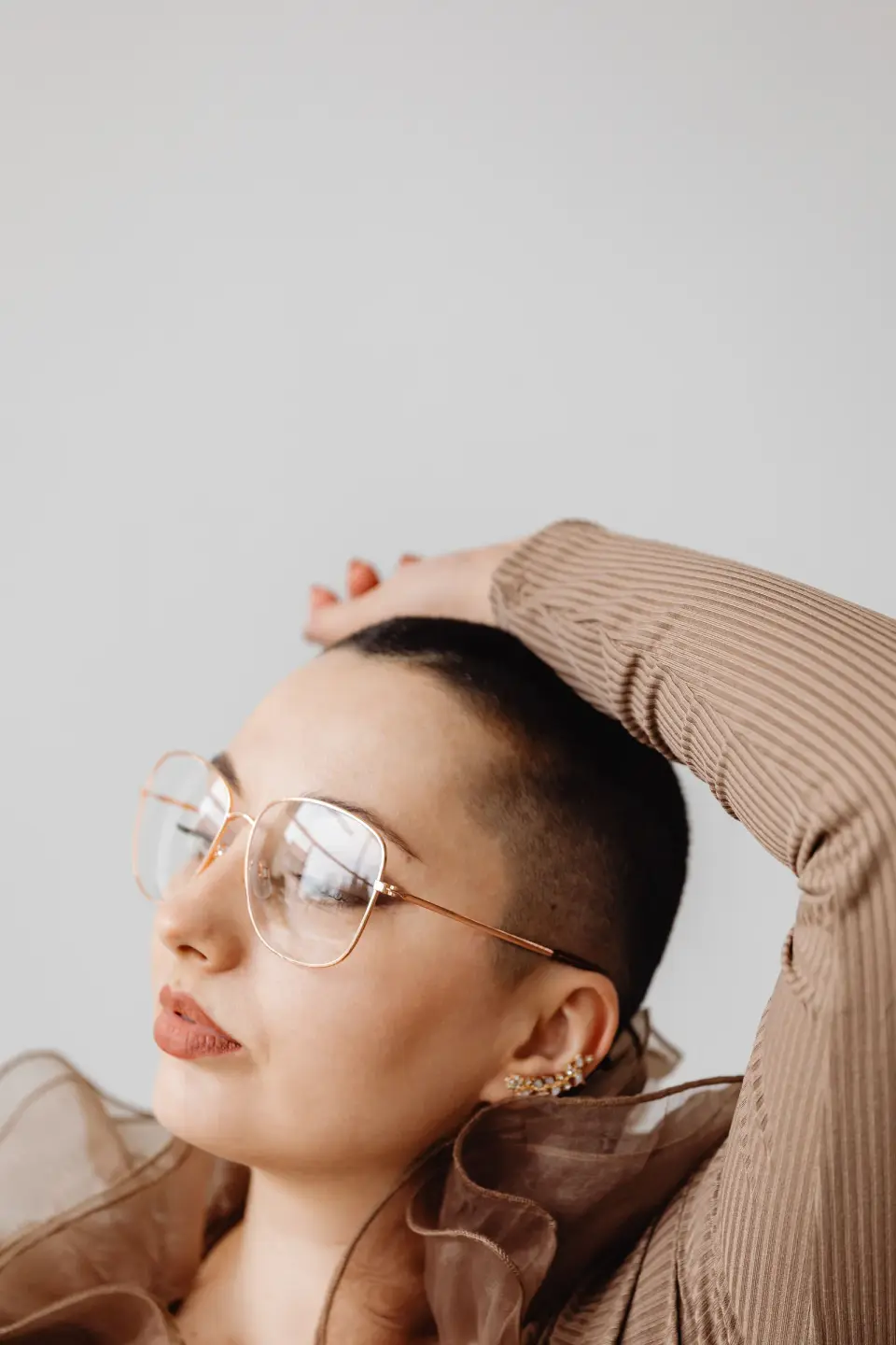 Woman in thin gold wire-rim eyeglasses, minimalist studio fashion portrait
