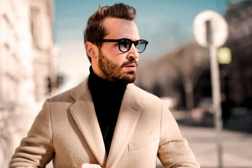 Bearded man in thick black acetate frames and a camel coat, street style portrait