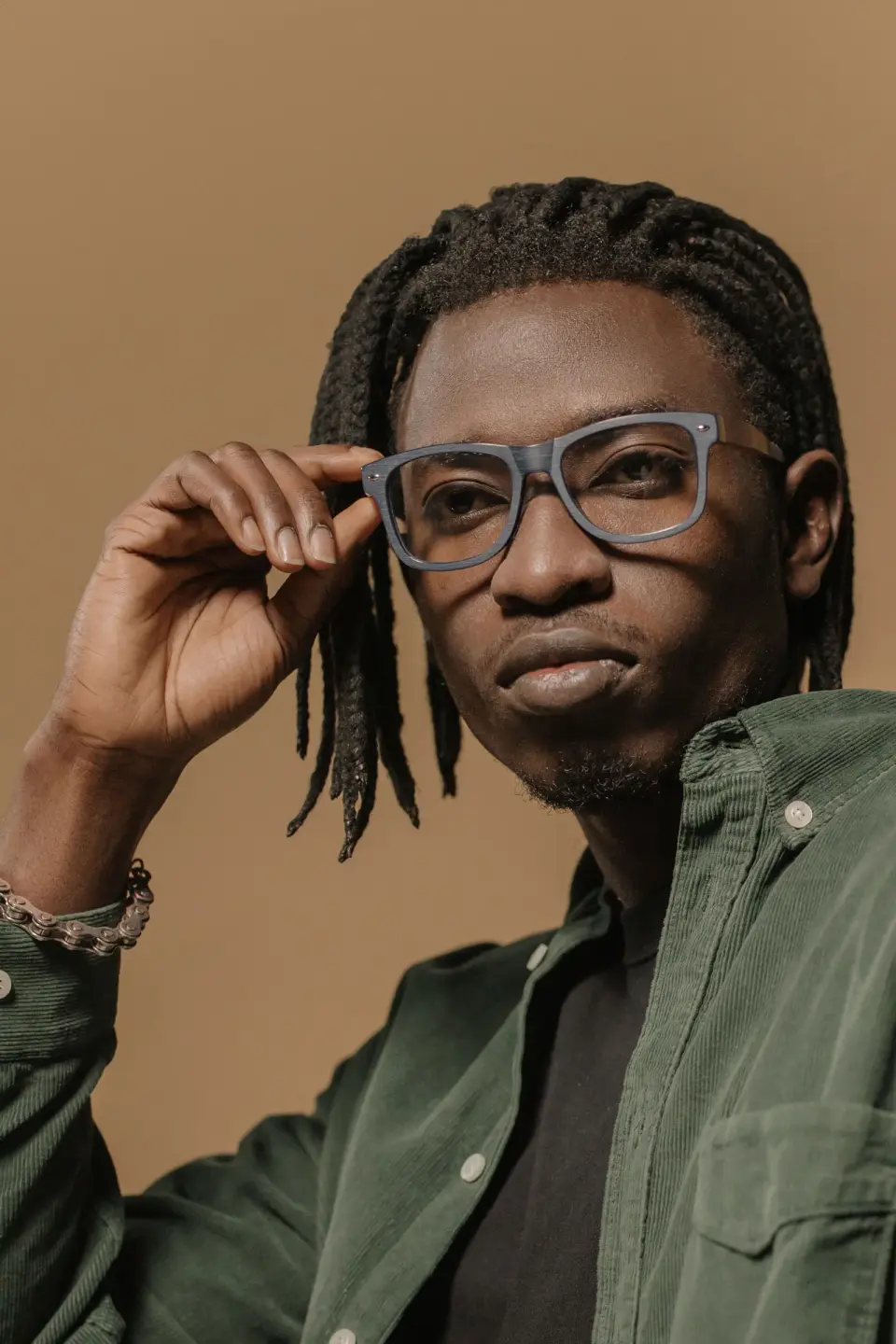 Man adjusting bold gray rectangular eyeglass frames, studio portrait