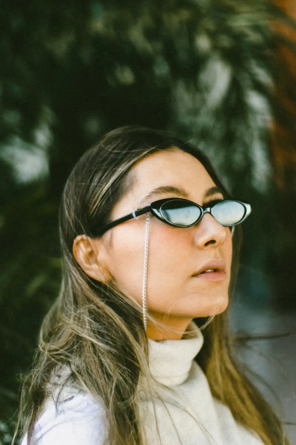 Woman in slim black oval sunglasses with an eyewear chain, outdoor portrait