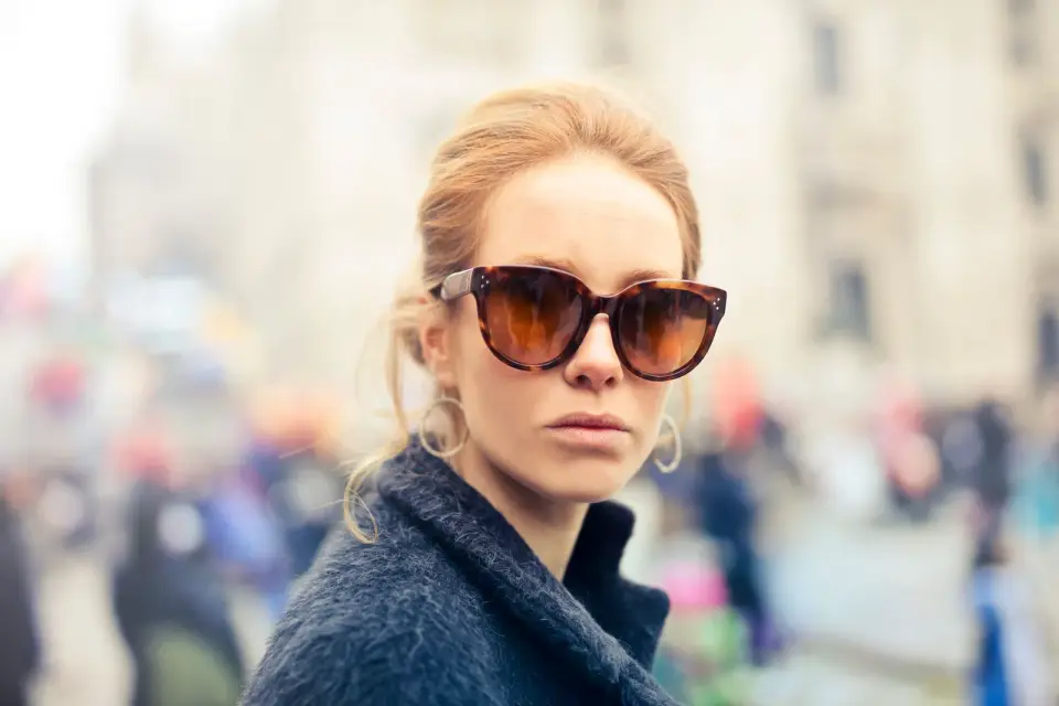 Woman in oversized tortoiseshell sunglasses on a city street, fashion portrait