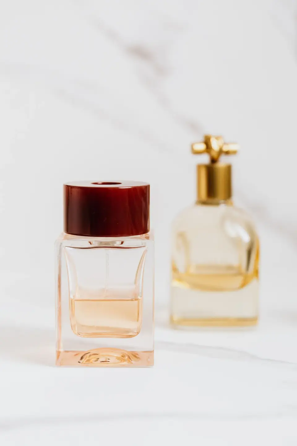 Two unbranded glass perfume bottles, one with a red cap and one with a gold cap