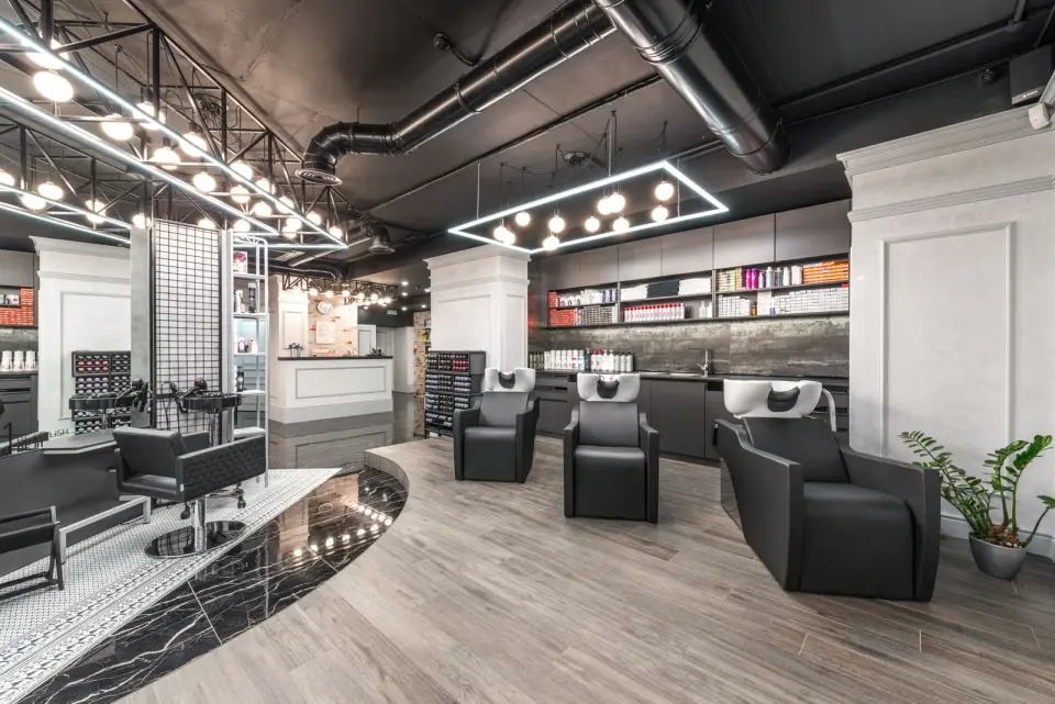 A modern hair salon with black backwash chairs, styling stations and shelves of hair care products