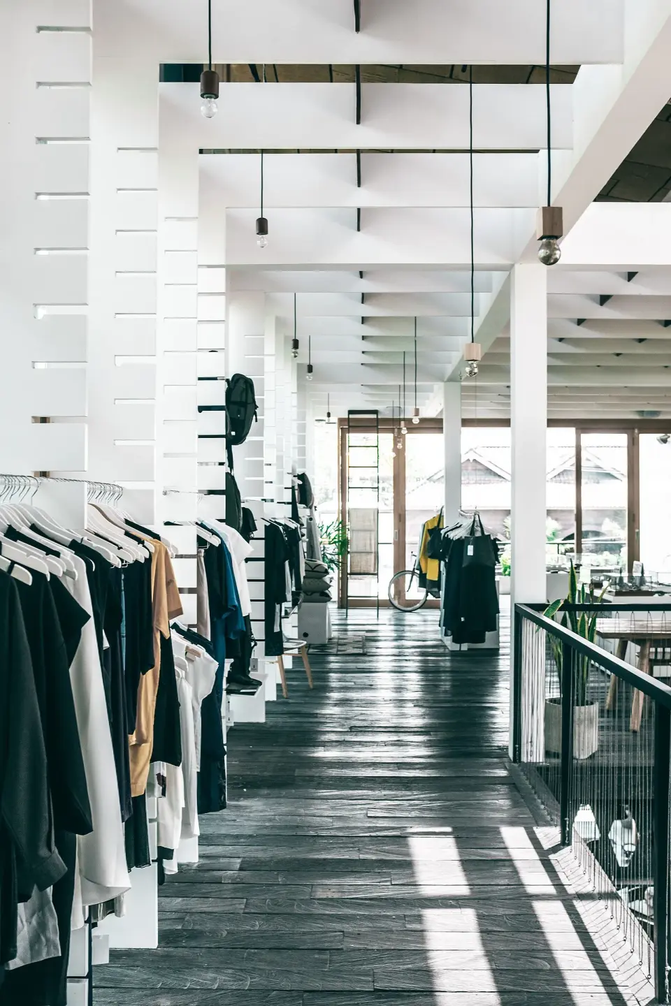 A bright fashion showroom with garments on white racks and a long open floor