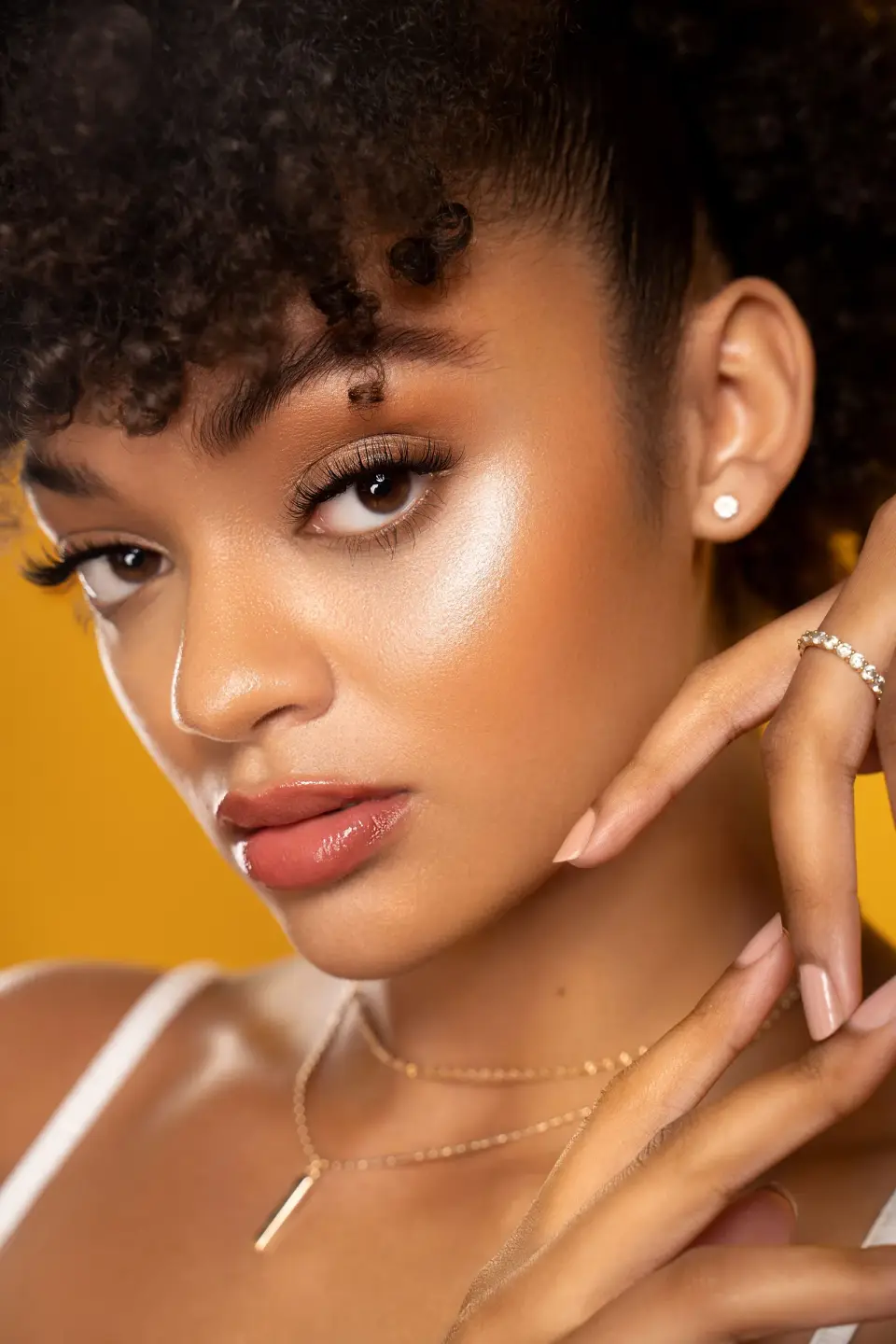 Woman with curly hair and glowing highlighted skin, beauty close-up