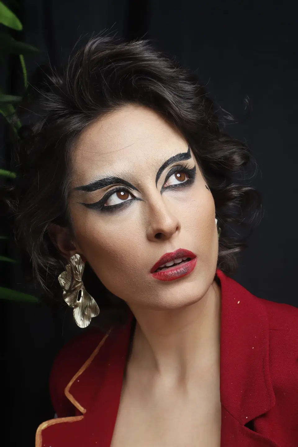 Woman with graphic black eyeliner, red lips and a red blazer, beauty portrait