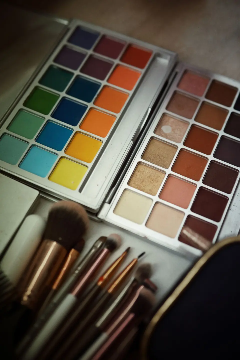 Bright and neutral eyeshadow palettes beside a set of makeup brushes