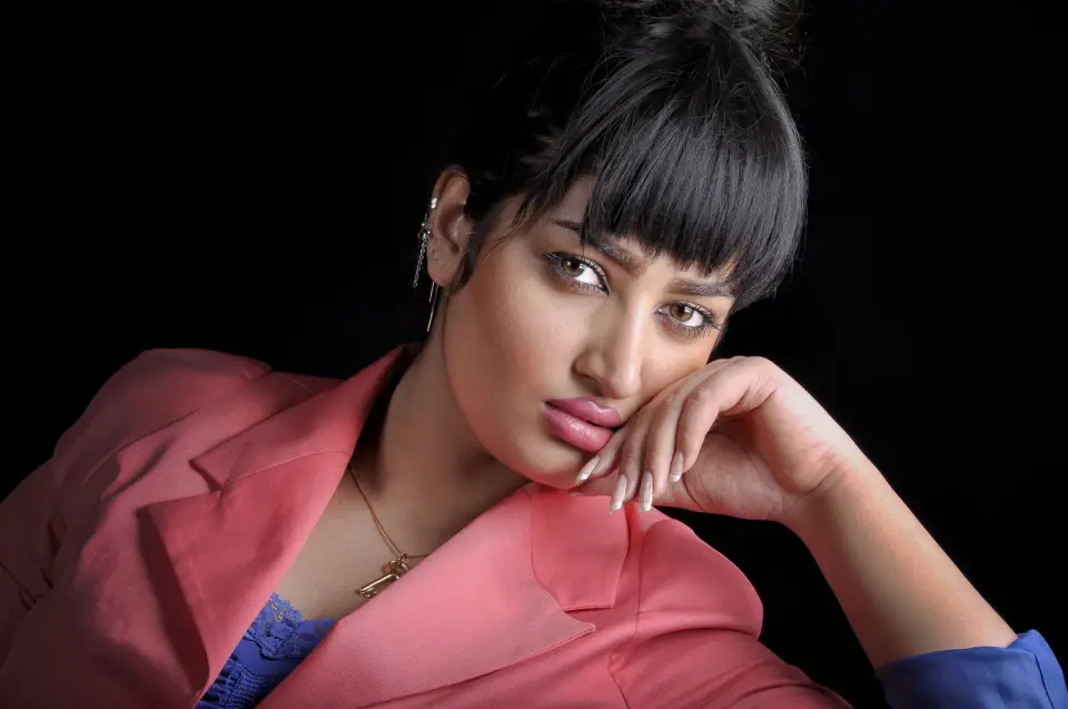 Woman with a blunt fringe in a peach blazer, studio fashion portrait