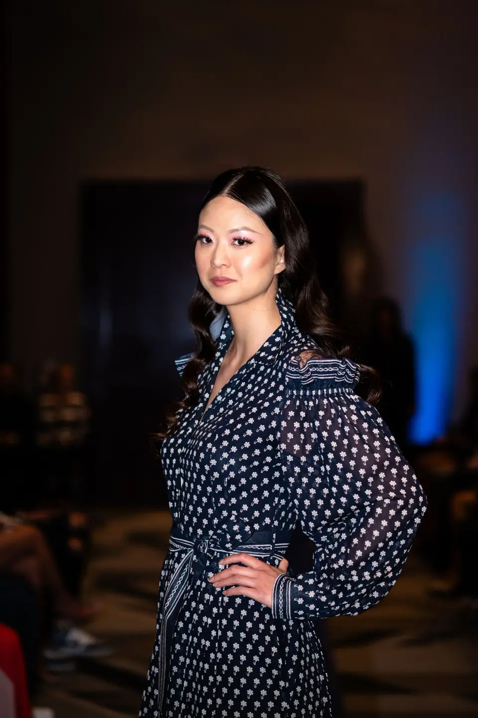 Woman in a navy printed dress with smocked shoulders at a fashion show