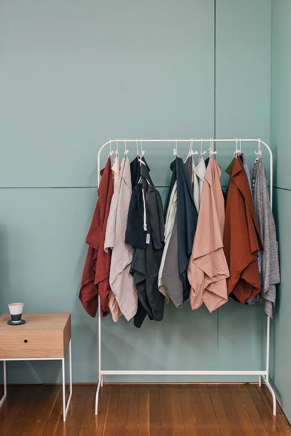Linen shirts in rust, pink, gray and black on a white rail in a showroom