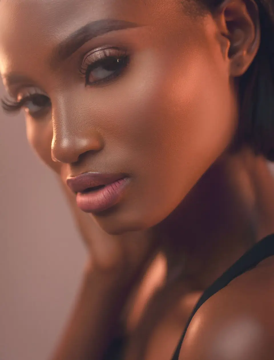 Woman with sculpted bronze makeup and nude lips, studio beauty portrait