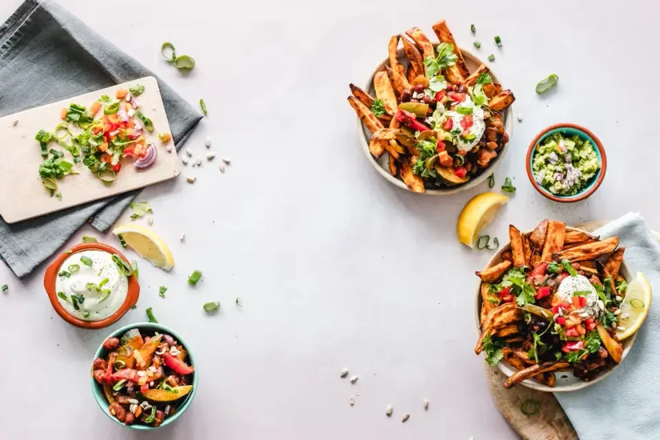 Sweet potato fries, guacamole and fresh vegetables photographed from above