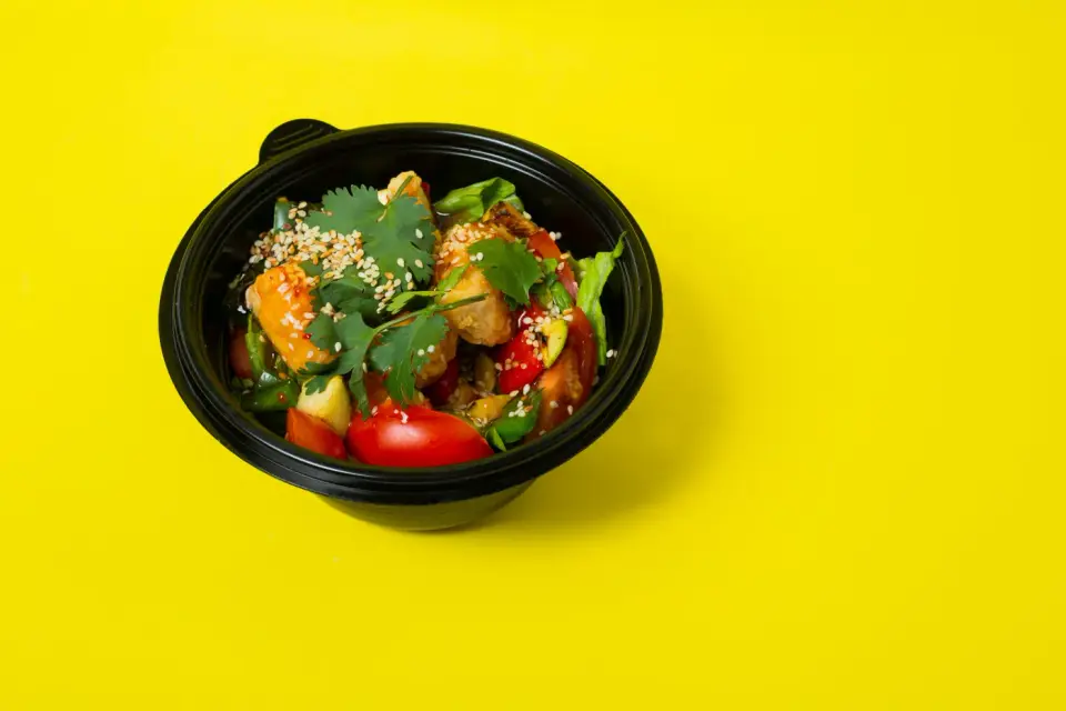 Colorful vegetable salad with sesame seeds on a bright yellow background