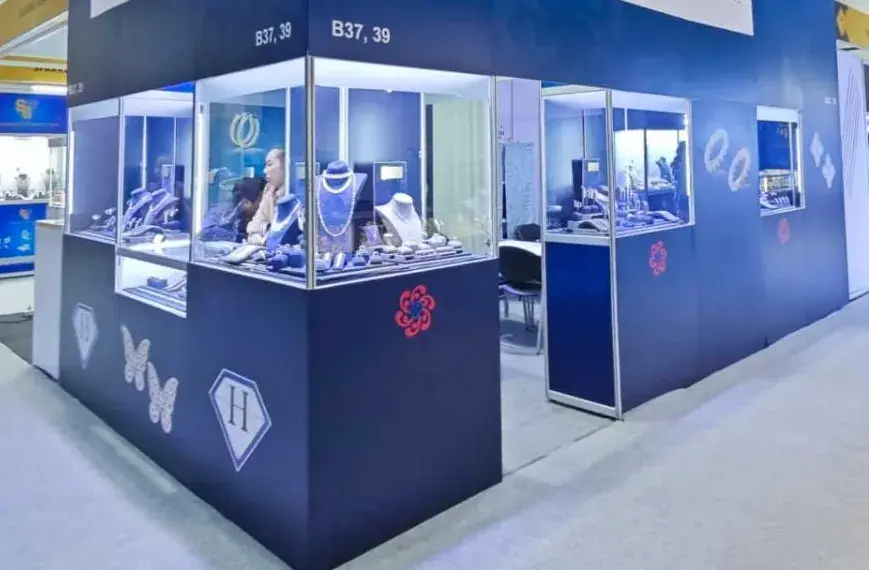 Lit glass jewelry showcases on the deep blue Highend Collections booth by Purple Exhibits