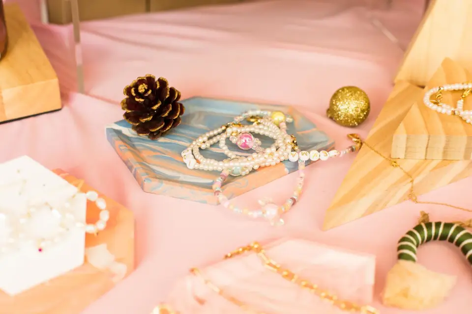 Pearl necklaces and bracelets arranged on a resin tray on a pink surface