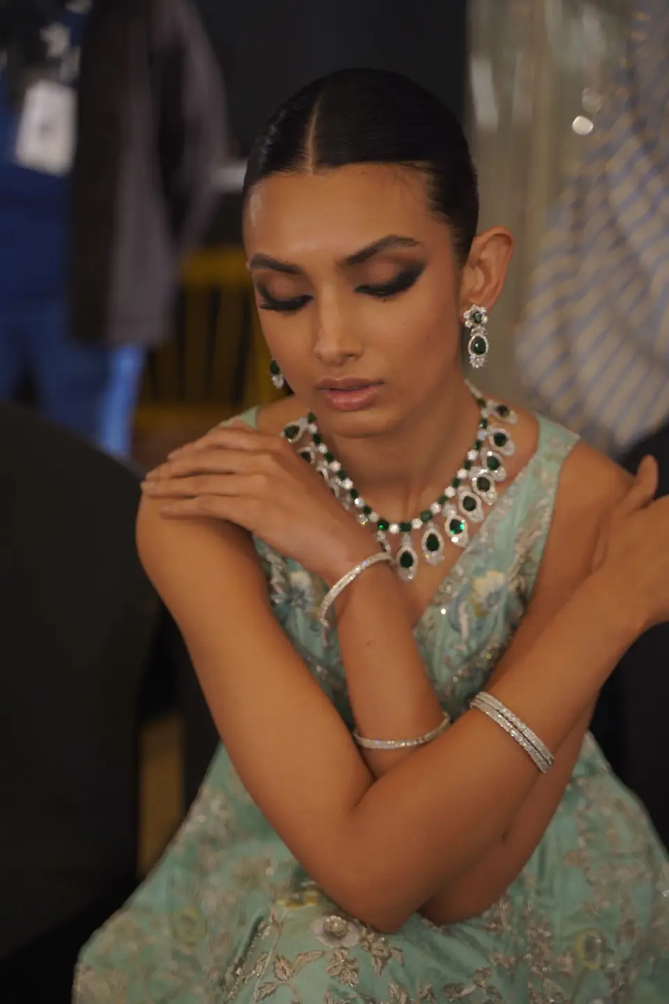 Woman in a mint dress wearing an emerald and diamond necklace, matching earrings and bangles