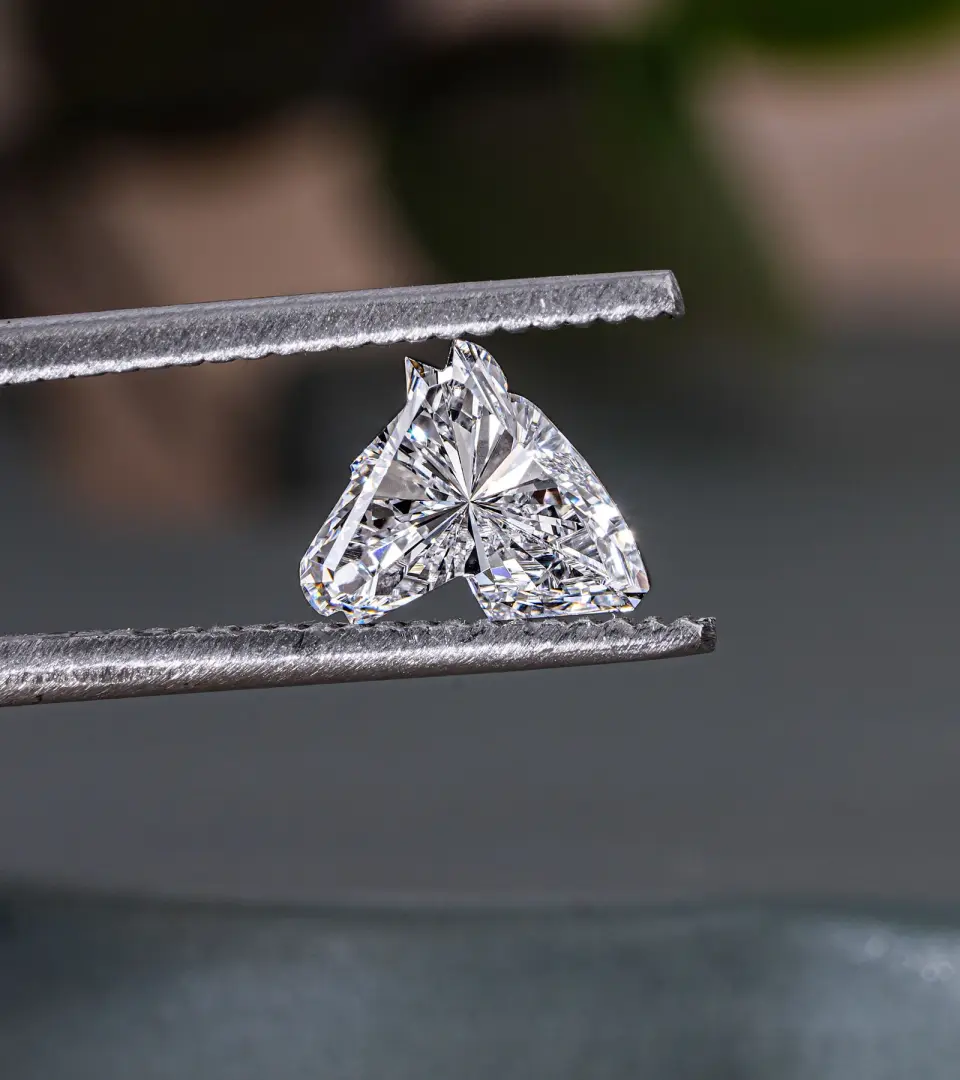 Heart-shaped loose diamond held in jeweler’s tweezers