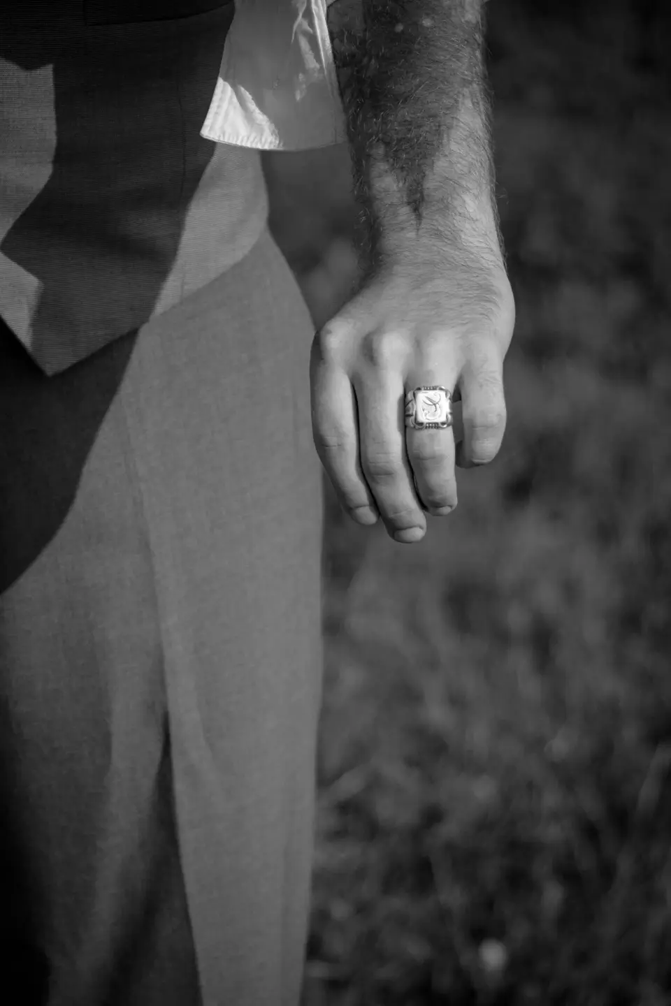 Man in a waistcoat wearing a silver signet ring, black and white close-up