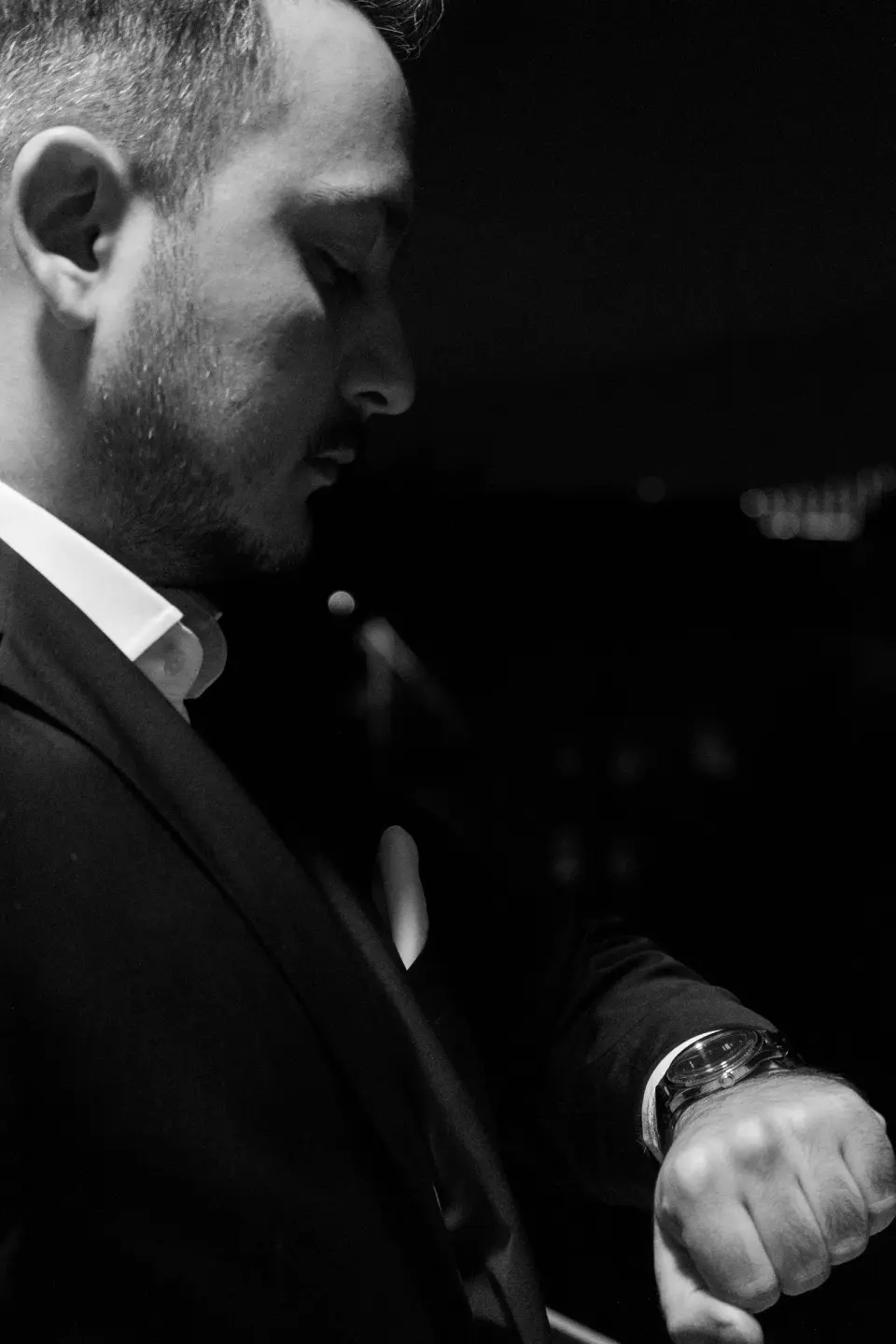 Man in a dark suit checking his wristwatch, black and white portrait