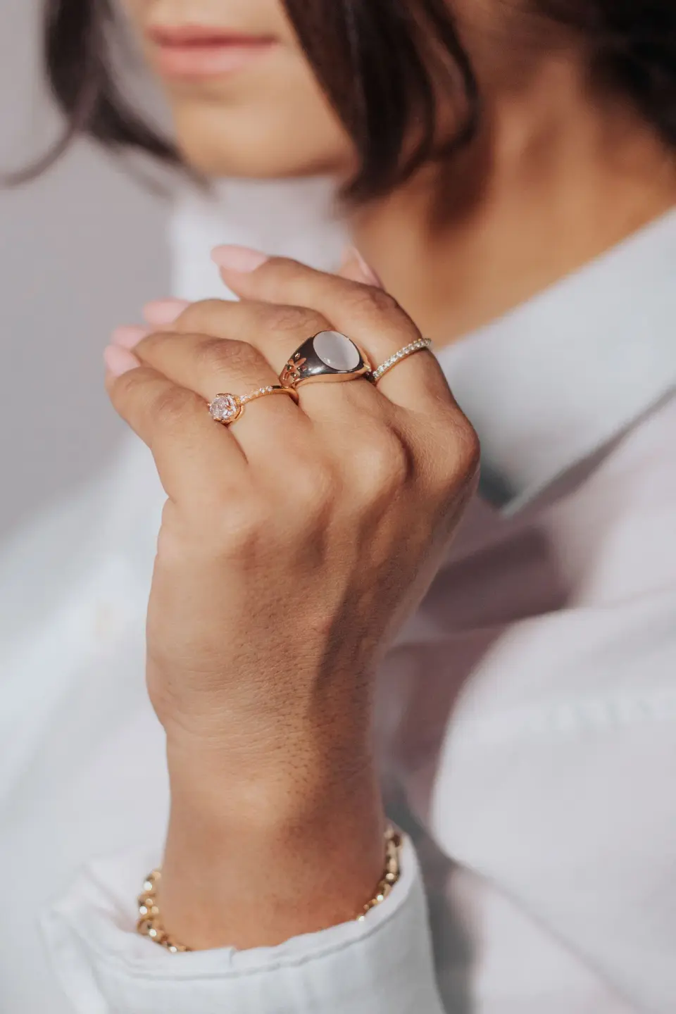 Stacked gold rings with a moonstone and a pink stone on a woman’s hand, close-up